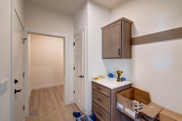 corridor featuring light wood-type flooring and baseboards