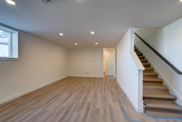 basement featuring light wood-style floors, recessed lighting, stairway, and baseboards