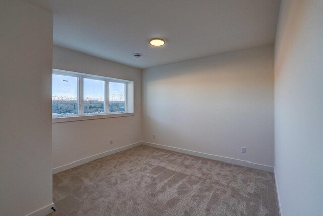 empty room featuring light carpet and baseboards