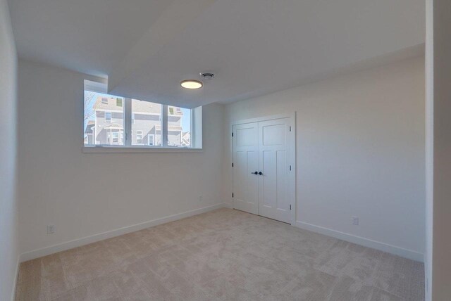 unfurnished room featuring light carpet and baseboards