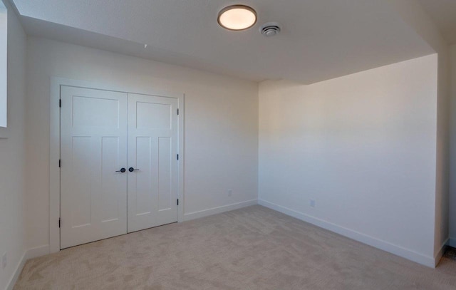 unfurnished bedroom featuring a closet, light carpet, and baseboards