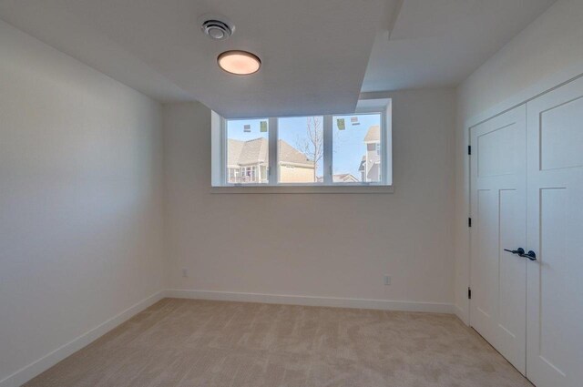 empty room featuring baseboards, visible vents, and light colored carpet