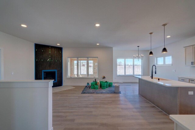 kitchen featuring recessed lighting, a fireplace, a sink, light countertops, and light wood-type flooring