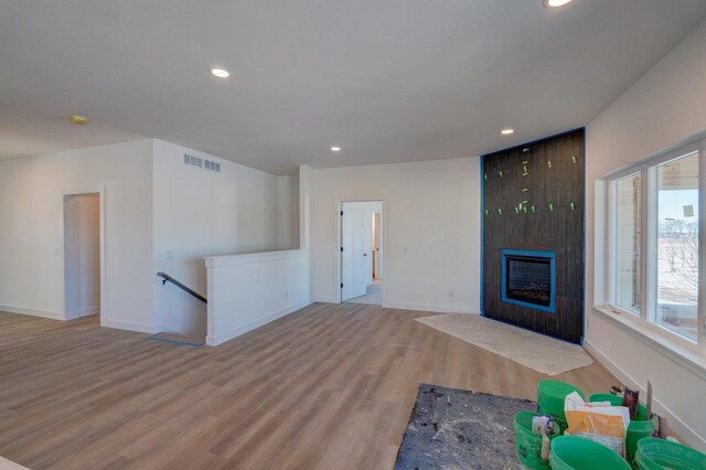 unfurnished living room with a fireplace, recessed lighting, visible vents, wood finished floors, and baseboards