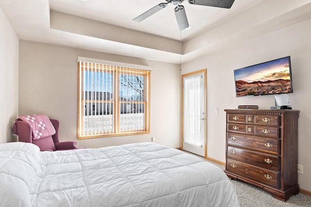 bedroom with ceiling fan, a tray ceiling, carpet, and baseboards