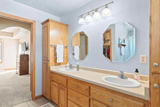 full bath featuring double vanity, tile patterned flooring, and a sink