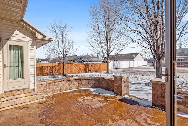 yard covered in snow with a patio, fence, and a residential view