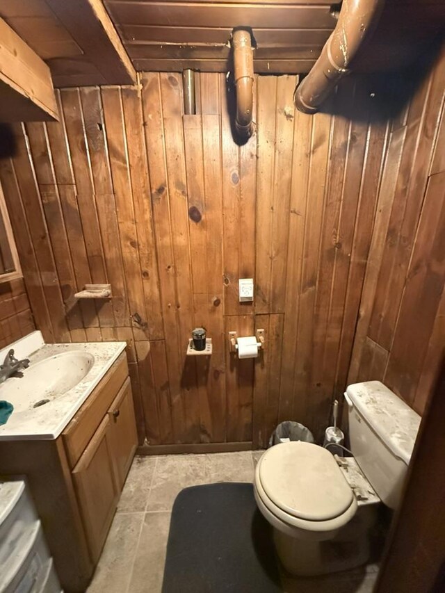 half bath featuring wooden walls, toilet, and vanity