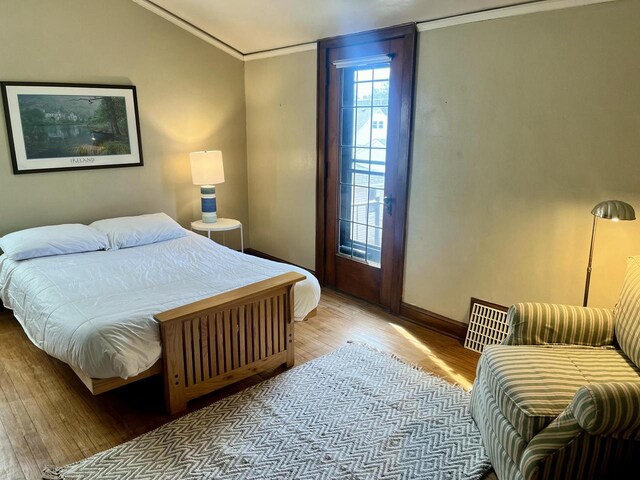 bedroom featuring visible vents, crown molding, baseboards, and wood finished floors