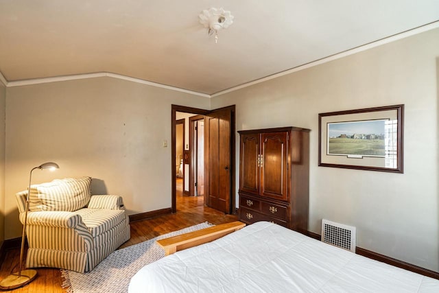 bedroom with crown molding, wood finished floors, and visible vents