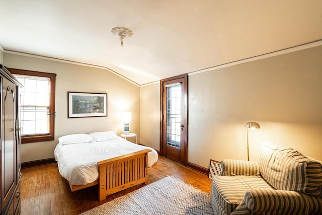 bedroom featuring lofted ceiling, baseboards, wood-type flooring, and ornamental molding