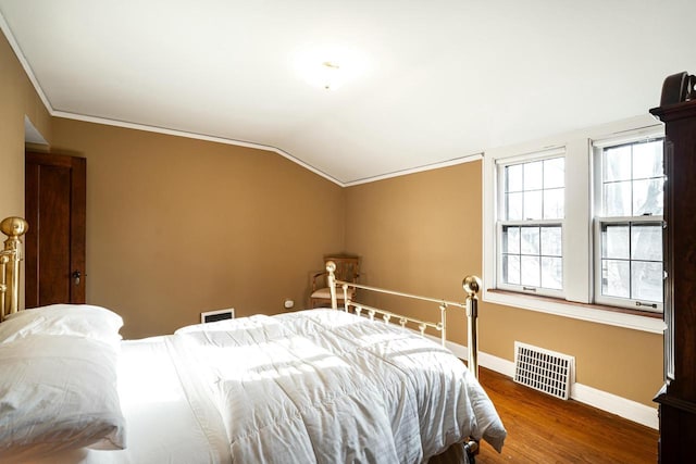 bedroom with visible vents, baseboards, lofted ceiling, ornamental molding, and wood finished floors