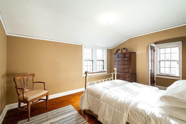 bedroom with multiple windows, dark wood finished floors, ornamental molding, and vaulted ceiling