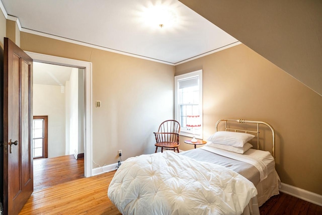 bedroom featuring wood finished floors, baseboards, and ornamental molding