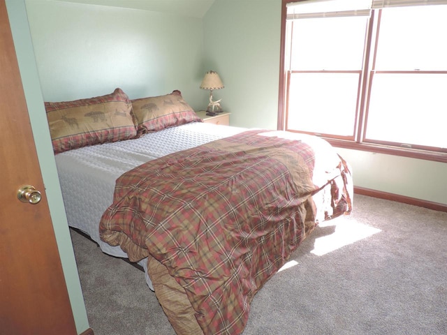 carpeted bedroom featuring baseboards and lofted ceiling