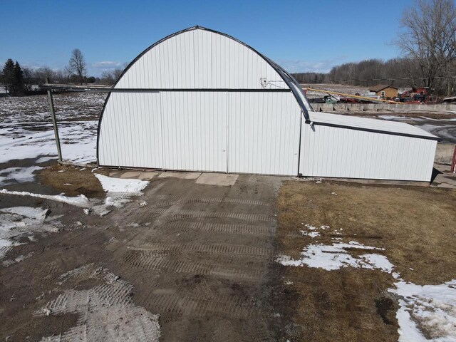 snow covered structure with an outbuilding and a pole building