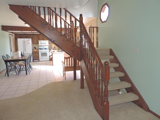 stairway with tile patterned flooring, carpet, and baseboards