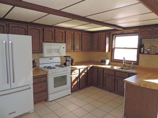 kitchen featuring light tile patterned flooring, white appliances, and a sink