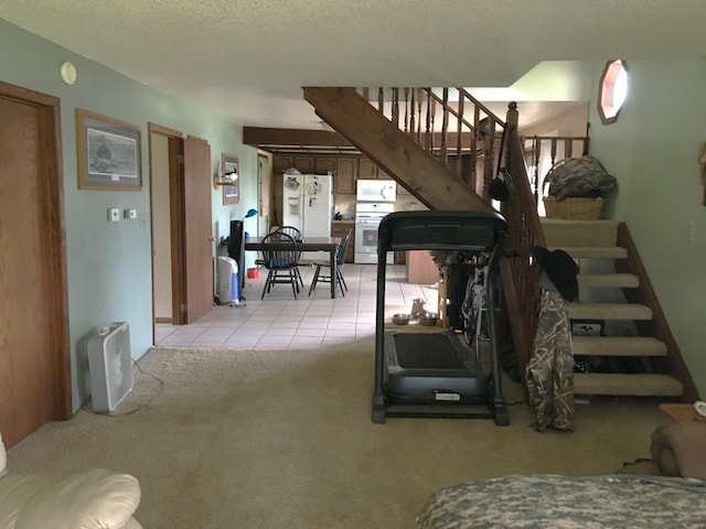 workout room featuring light carpet, a textured ceiling, and light tile patterned flooring