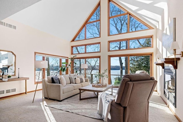 living area with carpet, a glass covered fireplace, visible vents, and baseboards