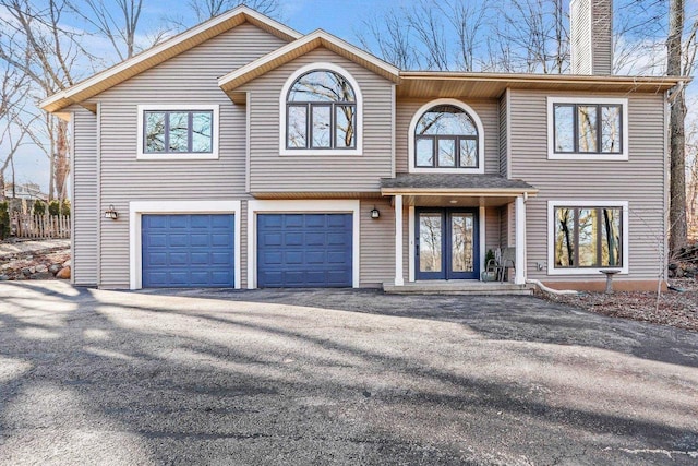 view of front of house featuring driveway, a chimney, and an attached garage