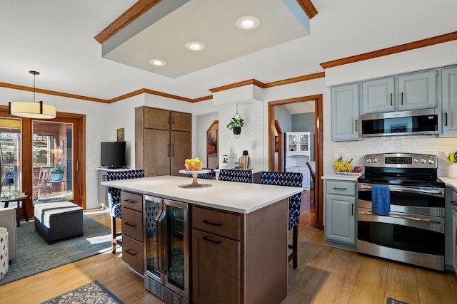 kitchen with appliances with stainless steel finishes, wine cooler, wood-type flooring, and a breakfast bar area