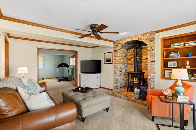 carpeted living room featuring a ceiling fan, a wood stove, crown molding, and baseboards