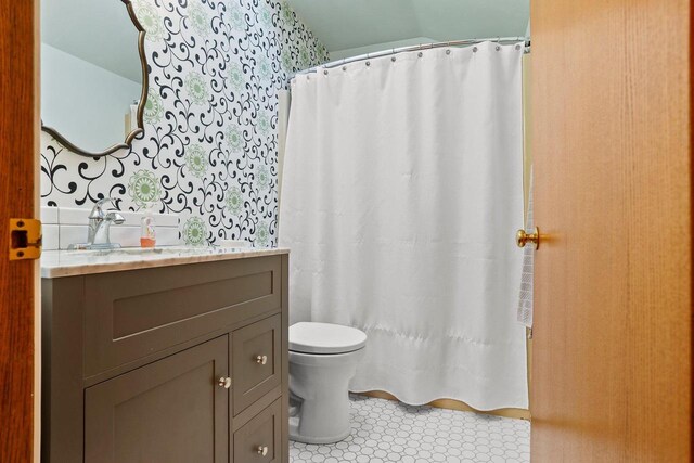 full bath featuring toilet, vanity, and a shower with curtain