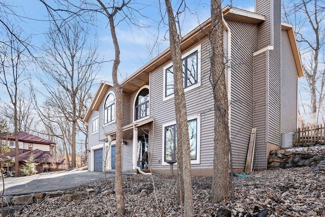 view of side of property featuring driveway, a chimney, and an attached garage