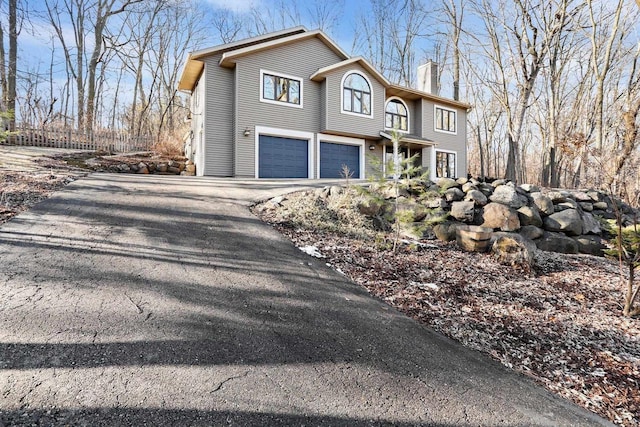 traditional home with driveway, a garage, and a chimney