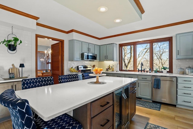 kitchen featuring stainless steel appliances, light wood-type flooring, light countertops, and backsplash