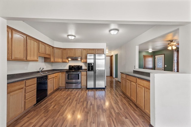 kitchen featuring under cabinet range hood, a sink, appliances with stainless steel finishes, dark wood-style floors, and dark countertops