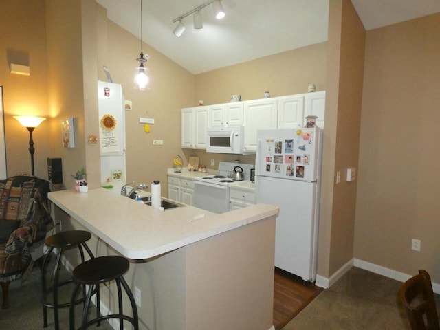 kitchen with a breakfast bar area, a peninsula, white appliances, a sink, and vaulted ceiling