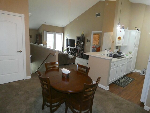 dining room with high vaulted ceiling, visible vents, dark carpet, and baseboards