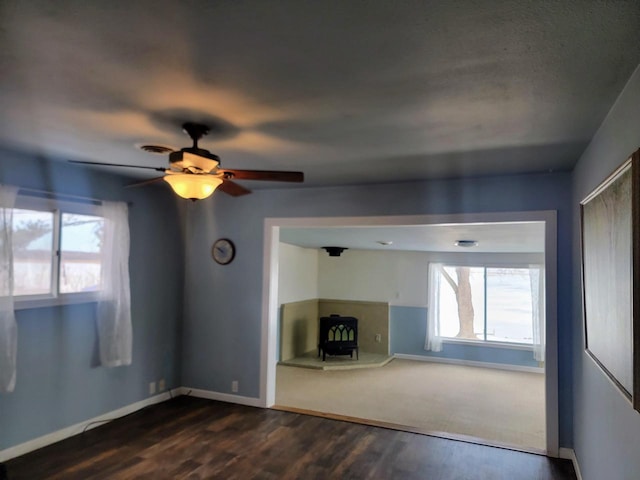 unfurnished living room with dark wood finished floors, a wood stove, and a healthy amount of sunlight