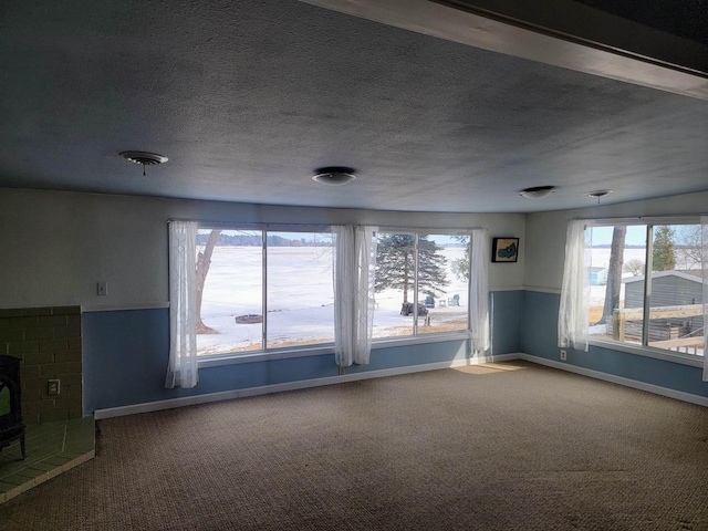 empty room featuring carpet flooring, a textured ceiling, and baseboards