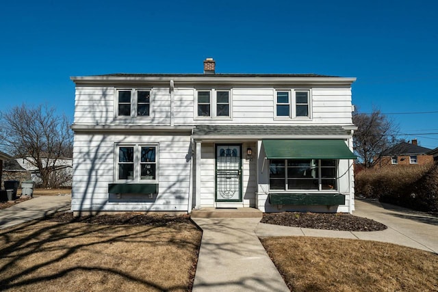 traditional-style house featuring central air condition unit, a shingled roof, and a chimney