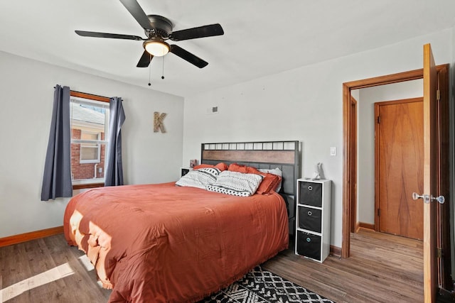 bedroom featuring ceiling fan, visible vents, baseboards, and wood finished floors