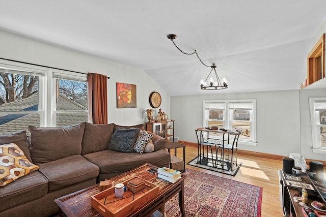 living room featuring lofted ceiling, an inviting chandelier, plenty of natural light, and light wood-style floors