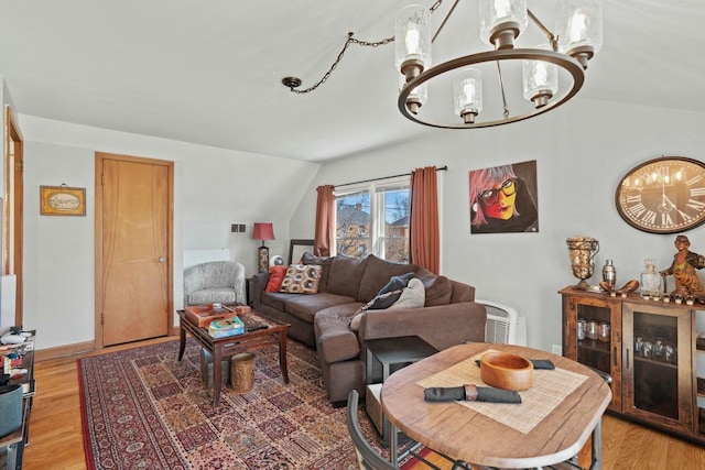 living room with a chandelier, lofted ceiling, light wood-style floors, and baseboards