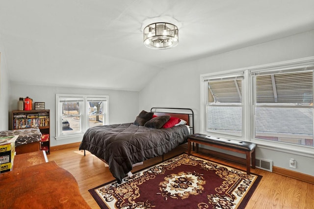 bedroom with vaulted ceiling, wood finished floors, and baseboards