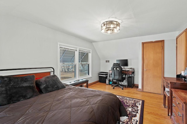 bedroom featuring lofted ceiling, light wood-style flooring, baseboards, and a notable chandelier