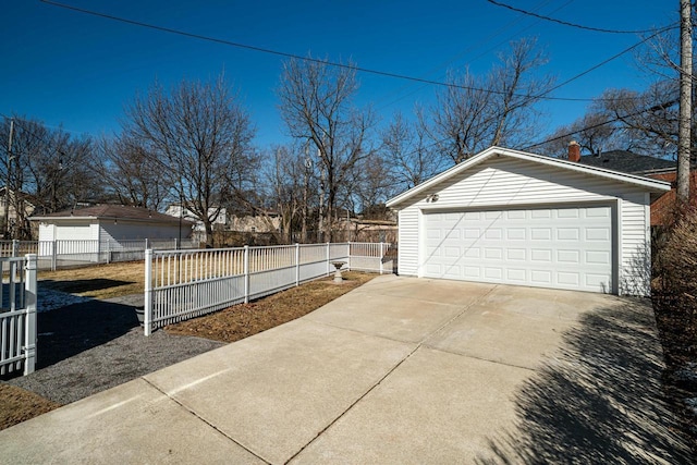 exterior space featuring a detached garage, fence, and an outbuilding