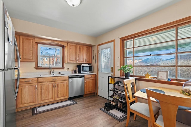 kitchen featuring light countertops, appliances with stainless steel finishes, a sink, and light wood-style floors