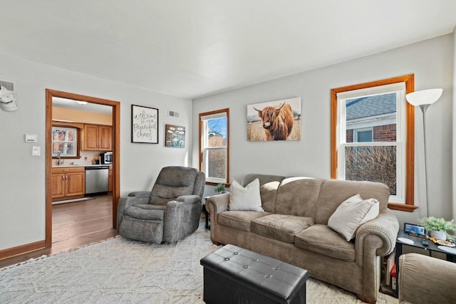 living area featuring light wood-style floors, visible vents, and baseboards