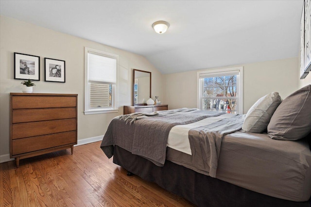 bedroom featuring lofted ceiling, wood finished floors, and baseboards