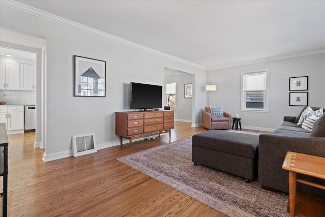 living room with light wood finished floors, visible vents, crown molding, and baseboards