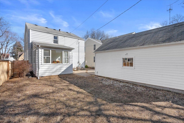 rear view of house featuring fence and a shingled roof