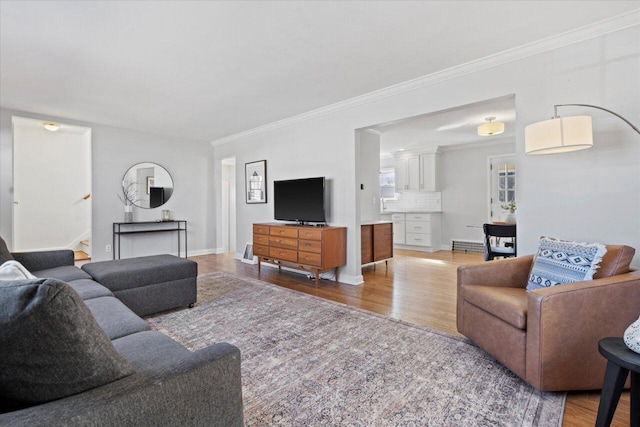 living room featuring crown molding, stairway, light wood-style floors, and baseboards