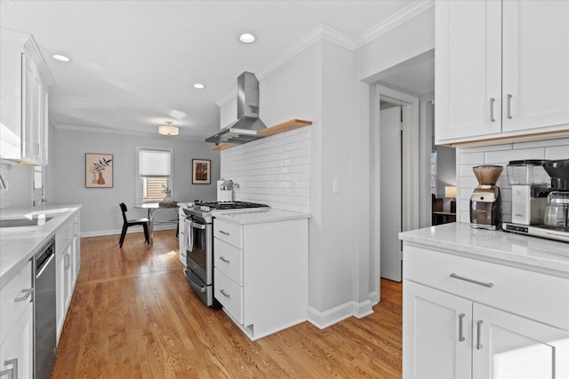 kitchen featuring appliances with stainless steel finishes, white cabinetry, crown molding, wall chimney range hood, and light wood-type flooring